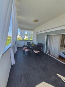 a dining room with a table and chairs and windows at Apartmani Marković RAB in Palit