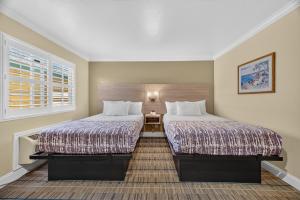 two beds in a small room with a window at Seaside Inn Monterey in Seaside