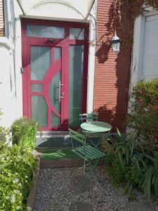 a red door with a table and a chair in front at L'Irisée in Liévin