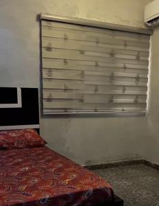 a bedroom with a bed and a window with a blind at M & A Homes Ilorin in Ilorin +1 photo
