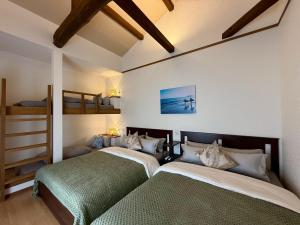 two beds in a room with two bunk beds at 鴨川ビーチハウス in Kamogawa