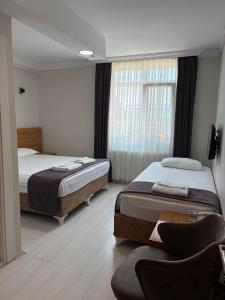 a bedroom with two beds and a chair and a window at Gölpark Otel in Yeniçağa