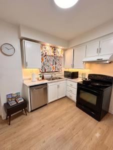 a kitchen with white cabinets and a black stove at Treverton Retreat in Toronto