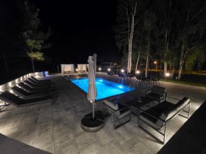 a swimming pool at night with chairs and an umbrella at Uvac lake "FF" in Sjenica