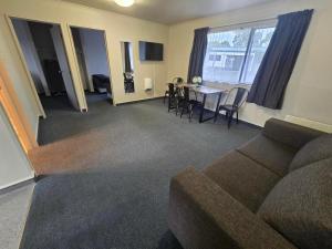 a living room with a couch and a table and chairs at Raceway Lodge in Feilding +3 photos
