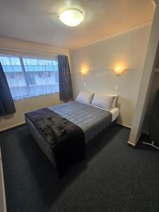 a bedroom with a bed and a large window at Raceway Lodge in Feilding