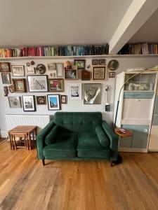 a green couch in a living room with a wall of pictures at Rubber Chicken House - Ramsgate in Ramsgate