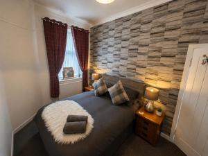 a bedroom with a king sized bed with a stone wall at Hillhead Apartment in Coylton