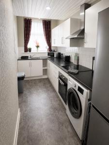 a kitchen with white cabinets and a washer and dryer at Hillhead Apartment in Coylton