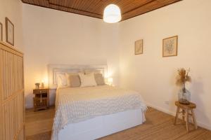 a bedroom with a white bed and a wooden ceiling at A casa da avó Tina in Montemor-o-Novo +11 photos
