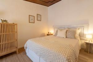 a bedroom with a white bed and a crib at A casa da avó Tina in Montemor-o-Novo