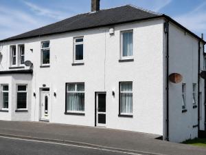a white house on the side of a street at Hillhead Apartment in Coylton
