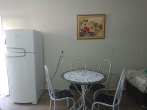 a table and chairs in a kitchen with a refrigerator at Pousada Paraíso in Telêmaco Borba