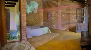a room with a bed in a brick wall at Kumaru Pousada e Restaurante in Palmeiras