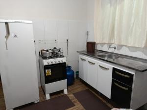 a small kitchen with a stove and a sink at Pousada Paraíso in Telêmaco Borba