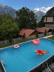 a large swimming pool with three inflatable boats on it at Thethi Paradise Hotel & Restaurant in Theth
