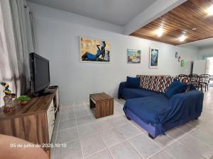 a living room with a blue couch and a tv at Paraíso em Juquehy in Juquei