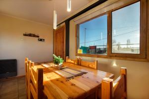 a dining room with a wooden table and a large window at Complejo Casa Roja in Dina Huapi