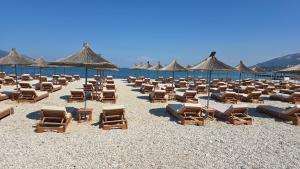 a bunch of chairs and umbrellas on a beach at Onde Rooms in Vlorë