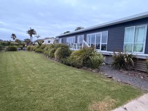 a house with a yard in front of it at Black Box Bach in Coopers Beach