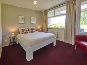 a bedroom with a bed with a window and a red couch at Laurahoeve in Nederweert