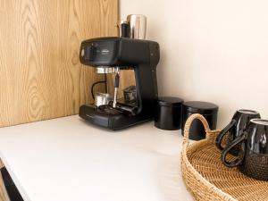 a black coffee maker on a counter next to a basket at Pine Grove Retreat in Auckland +10 photos