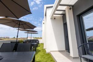 a patio with tables and chairs with umbrellas at White Pampas Tiny houses in Paralia Dionysiou