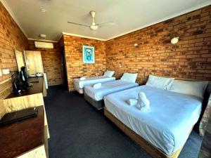 two beds in a room with a brick wall at Merimbula Coastline Motel in Merimbula