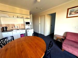 a living room with a wooden table and a couch at Merimbula Coastline Motel in Merimbula