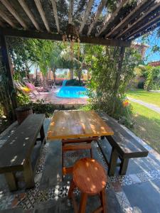 a wooden picnic table and a chair under a pergola at Mar Doce Lar - Praia Macapa in Luis Correia
