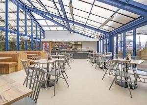 a dining room with tables and chairs and windows at The Casa Descanso in Rhyl