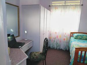 a bedroom with a bed and a desk with a laptop at Gazebo in Port-of-Spain