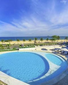 a large swimming pool with the beach in the background at Icônico Hotel Nacional in Rio de Janeiro