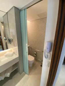 a bathroom with a toilet and a sink and a phone at Icônico Hotel Nacional in Rio de Janeiro