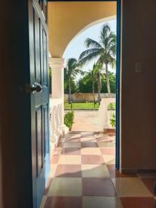 an open door to a porch with palm trees in the background at Hotel Hacienda IMI 3 in Imí