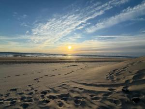 a sunset on a beach with footprints in the sand at Petit nid chaleureux in Mimizan