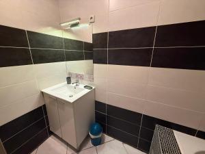 a bathroom with a sink and black and white tiles at Petit nid chaleureux in Mimizan