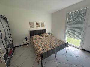 a bedroom with a bed and a large window at Petit nid chaleureux in Mimizan