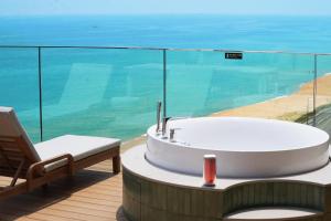 a tub and a chair on a balcony with the ocean at 클리프비치 in Sangun-ni