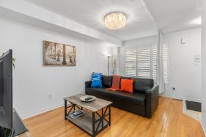 a living room with a black couch and a table at Semi-Private Townhouse - 3 Bedrooms, 4 beds, Free Parking, Wifi, Netflix, - Hosted by Matthew in Toronto