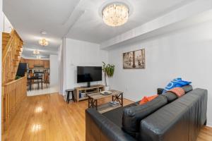 a living room with a black leather couch and a television at Semi-Private Townhouse - 3 Bedrooms, 4 beds, Free Parking, Wifi, Netflix, - Hosted by Matthew in Toronto