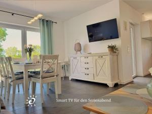 a dining room with a table and a tv at Nordprinz mit Sauna und Whirlpool in Geestland