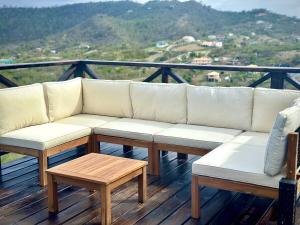 a white couch sitting on a deck with a table at Dover View Villas in Carriacou