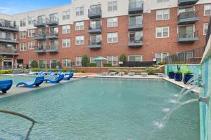 a swimming pool with blue chairs in front of a building at Walk to Toyota Stadium in Frisco