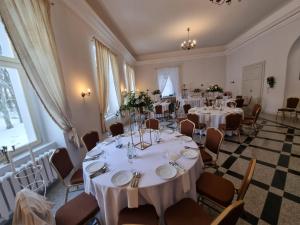 a room with tables and chairs with white tablecloths at Pałac w Dolsku in Dolsk