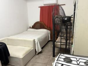 a small bedroom with a bed and a fan at Los Romanos farm in Sauce Bajada