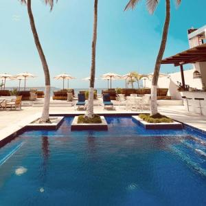 a swimming pool with palm trees in a resort at Wala Hotel and Beach Club in Cartagena de Indias