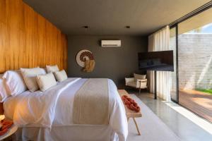 a bedroom with a large white bed and a television at Kamai Pousada Boutique in Pôrto de Pedras