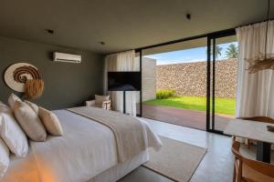a bedroom with a bed and a sliding glass door at Kamai Pousada Boutique in Pôrto de Pedras