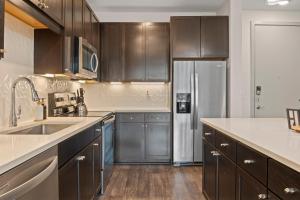 a kitchen with wooden cabinets and a stainless steel refrigerator at Walk to Toyota Stadium in Frisco +8 photos